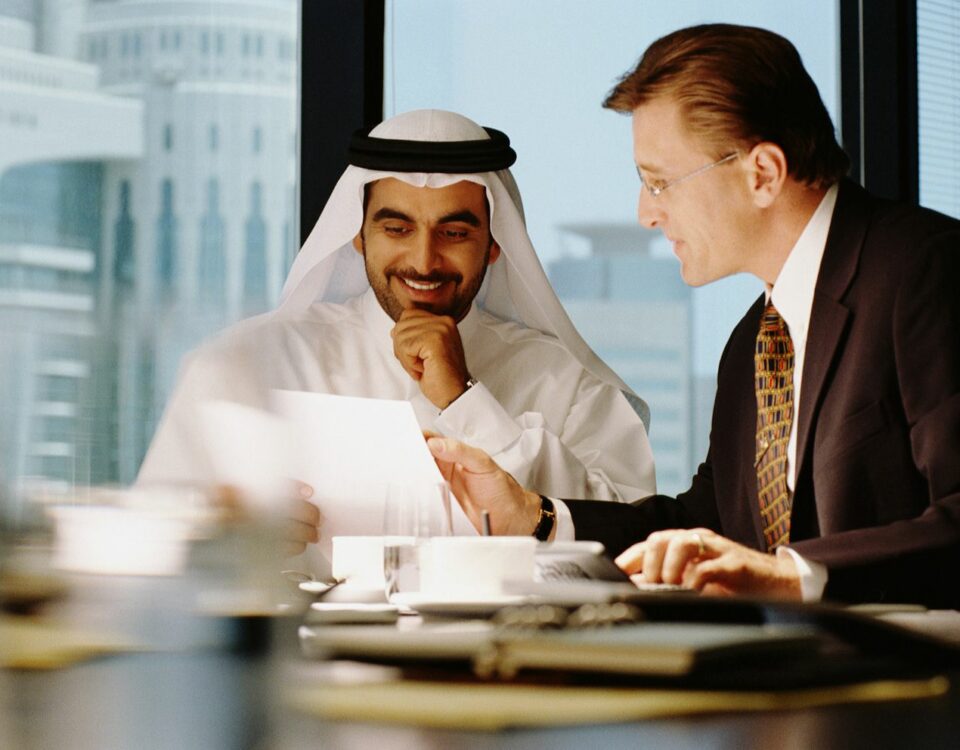 Two men discussing international commerce at a conference table.