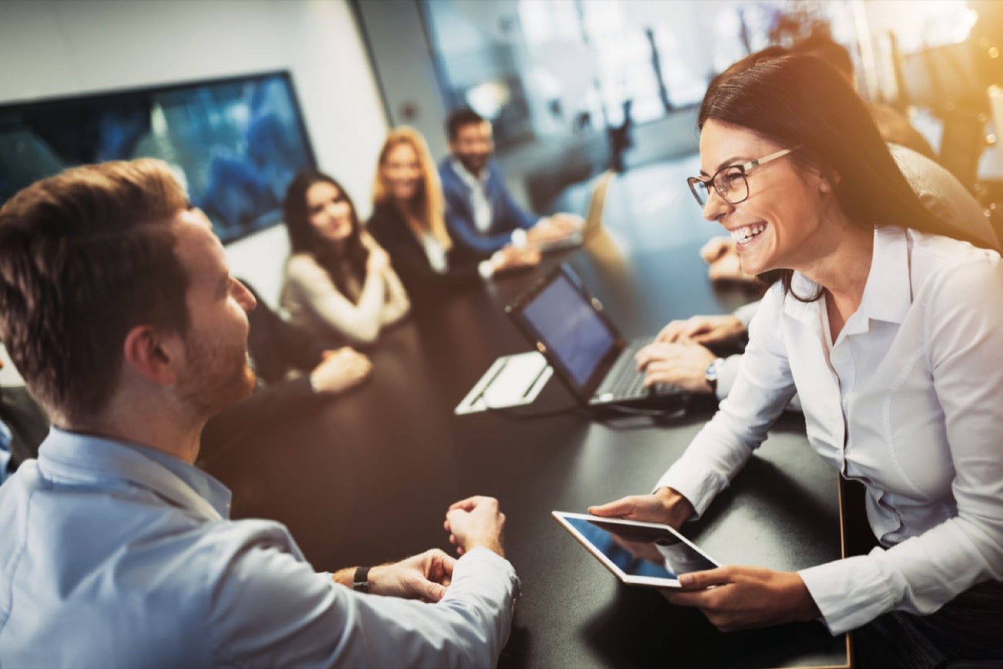 A group of people sitting around a table in a conference room, engaged in localization discussions for customer support.