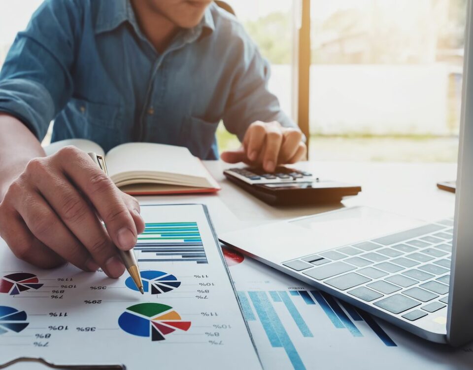 A man is working at a desk with a laptop and graphs, involved in financing trade.