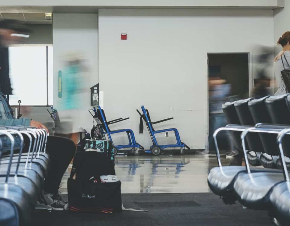 A group of people sitting in chairs at an airport, waiting to go through Customs and Border Protection.