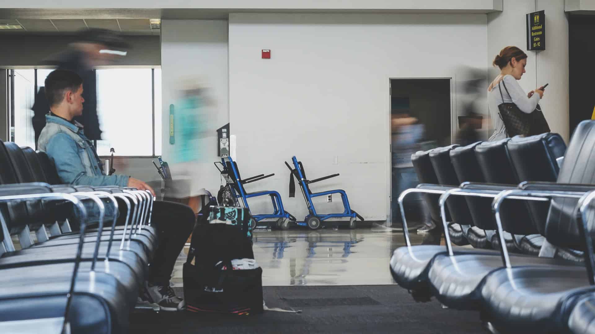 A group of people sitting in chairs at an airport, waiting to go through Customs and Border Protection.