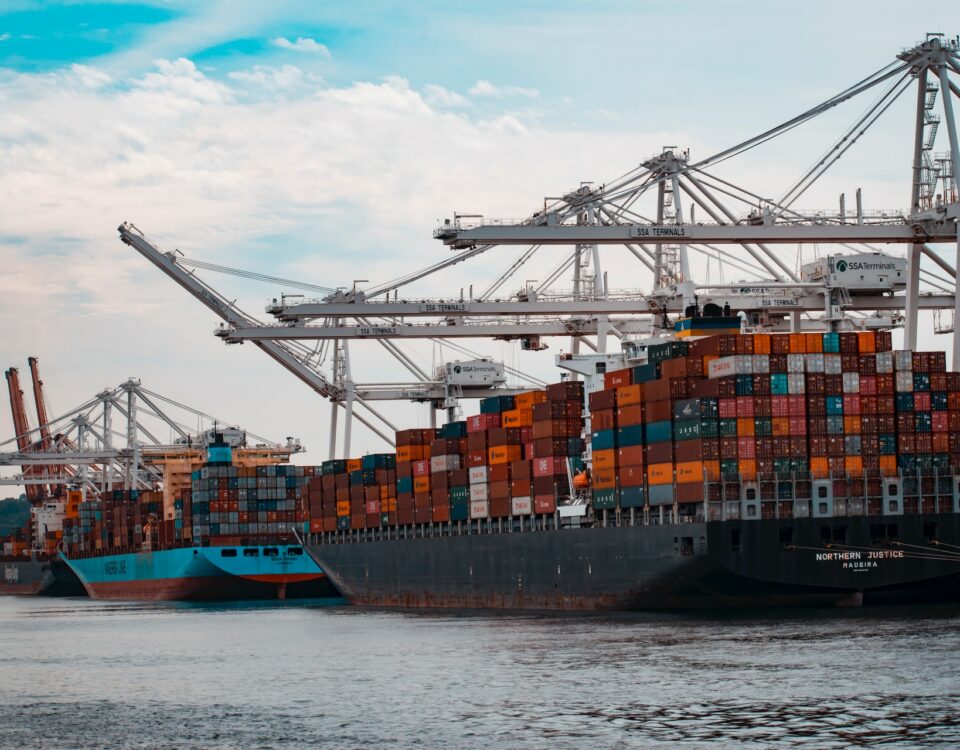 A container ship, carrying a wide range of products and services, docked in a harbor.