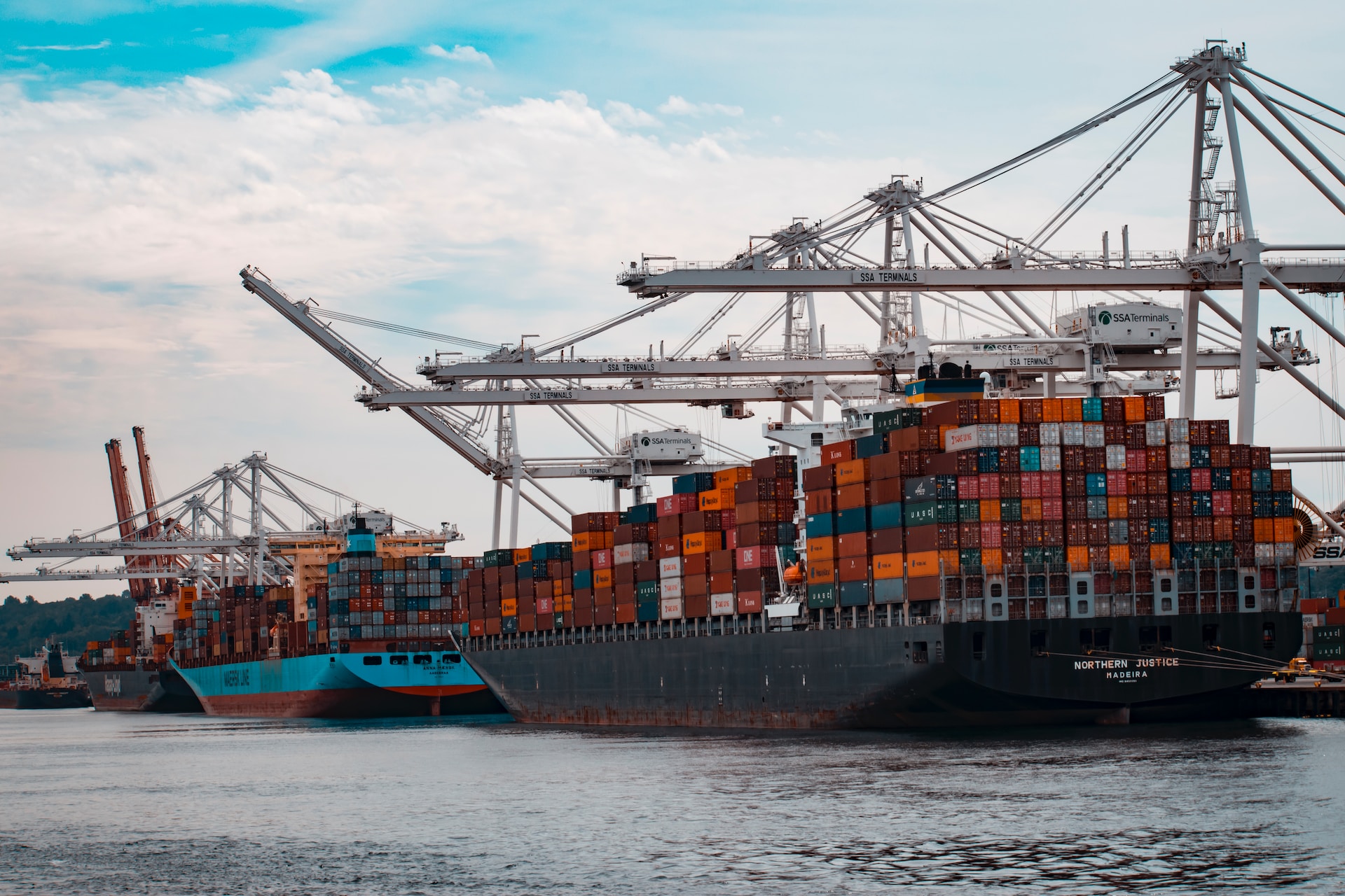 A container ship, carrying a wide range of products and services, docked in a harbor.