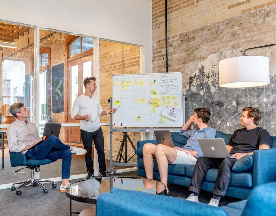 A group of people with a strong brand presence sitting around a table in an office, discussing strategies for entering foreign markets.