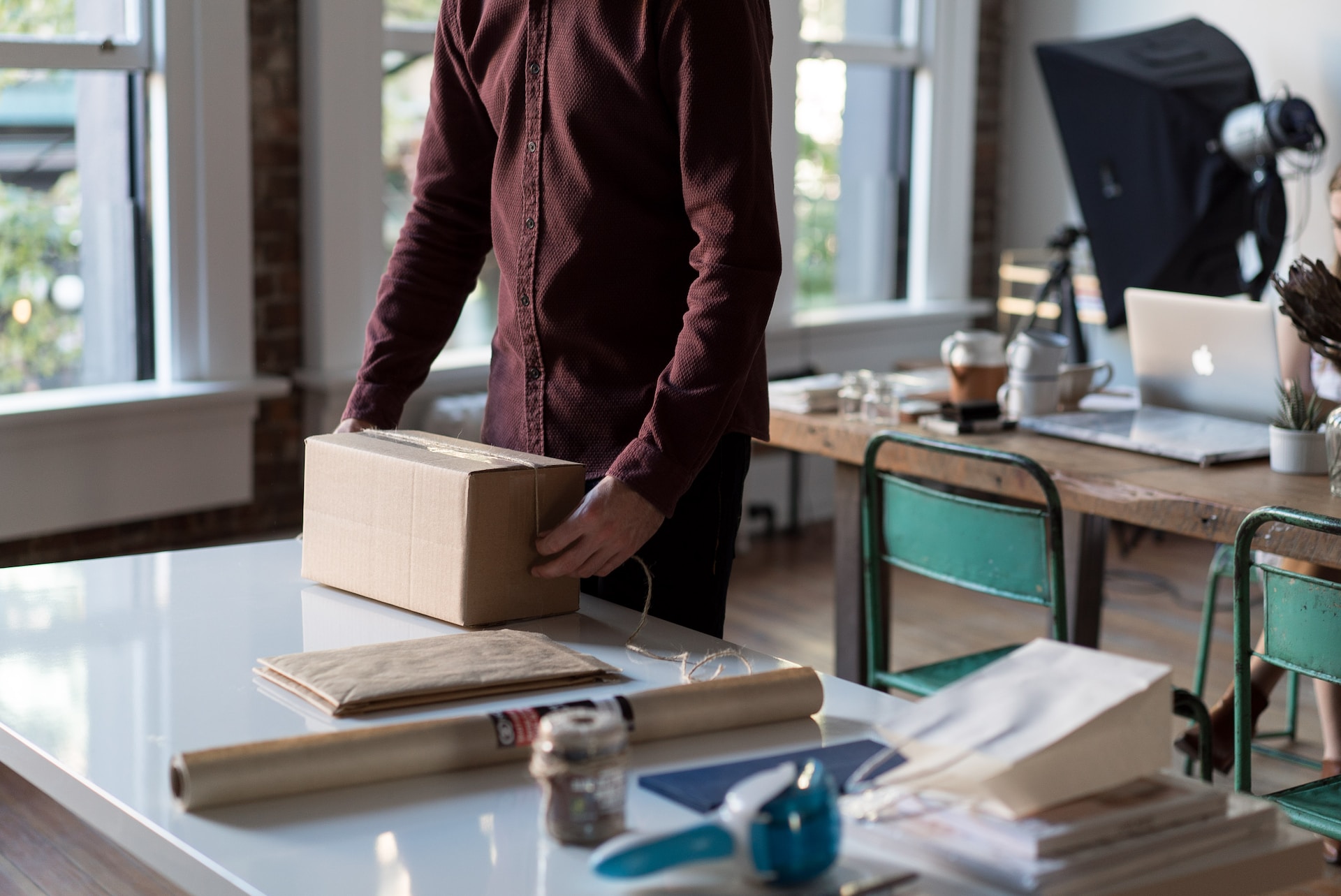 A man from a SME is holding a box in front of a desk, discussing export financing options.