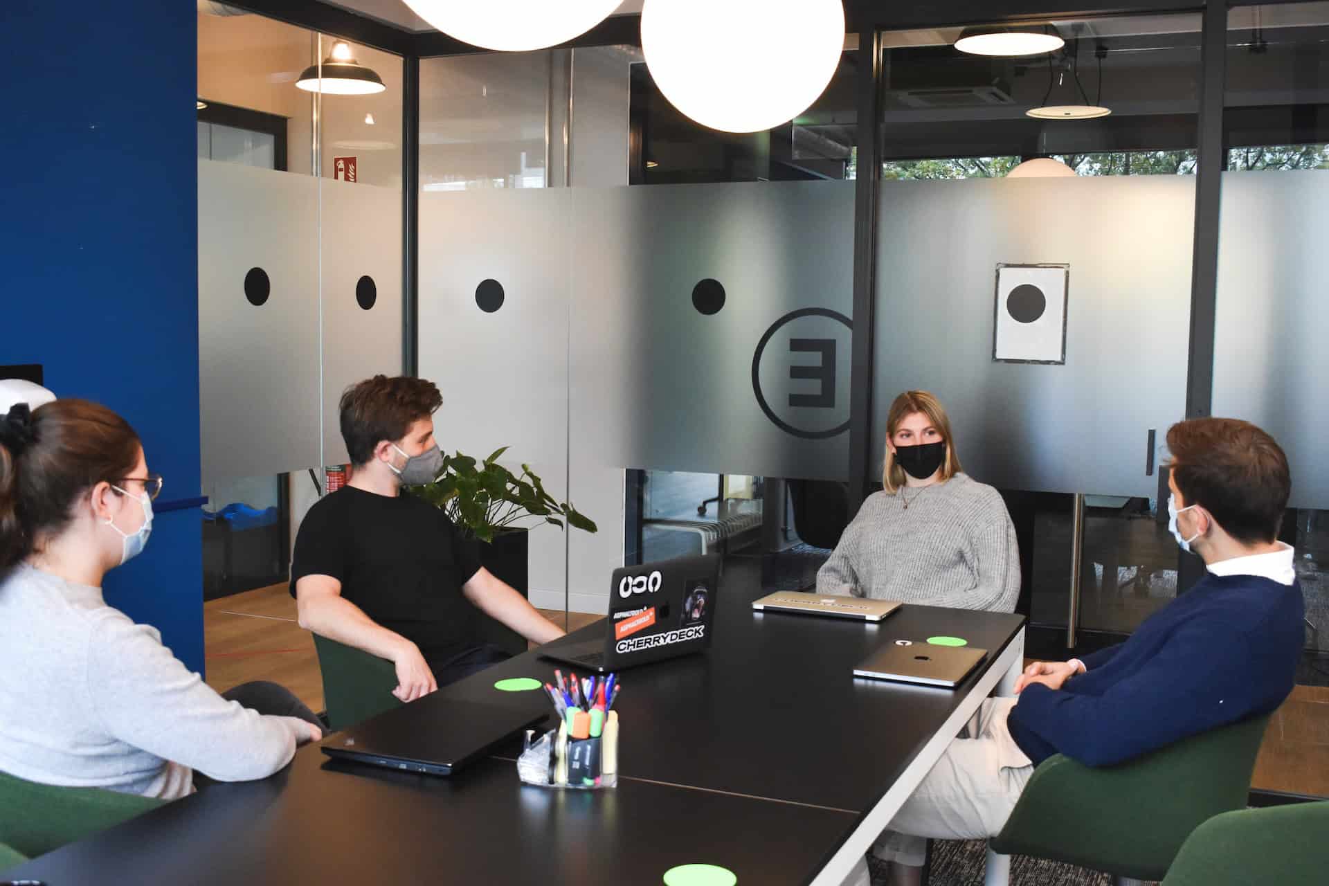 Amid the ongoing COVID-19 pandemic, a group of people is seated around a table in an office, discussing the effects of international trade.