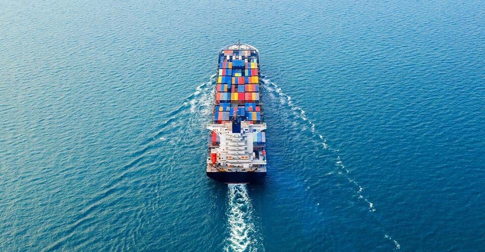 An aerial view of a container ship in the ocean providing export market analysis.