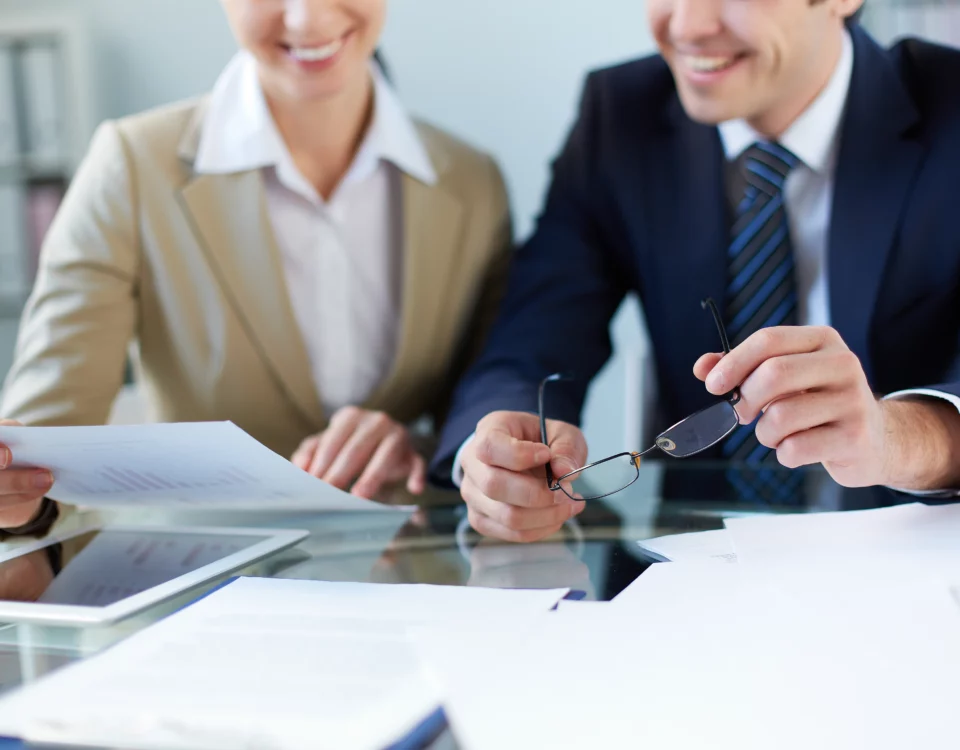 Two business people sitting at a desk practicing negotiation techniques while reviewing cross-cultural papers.