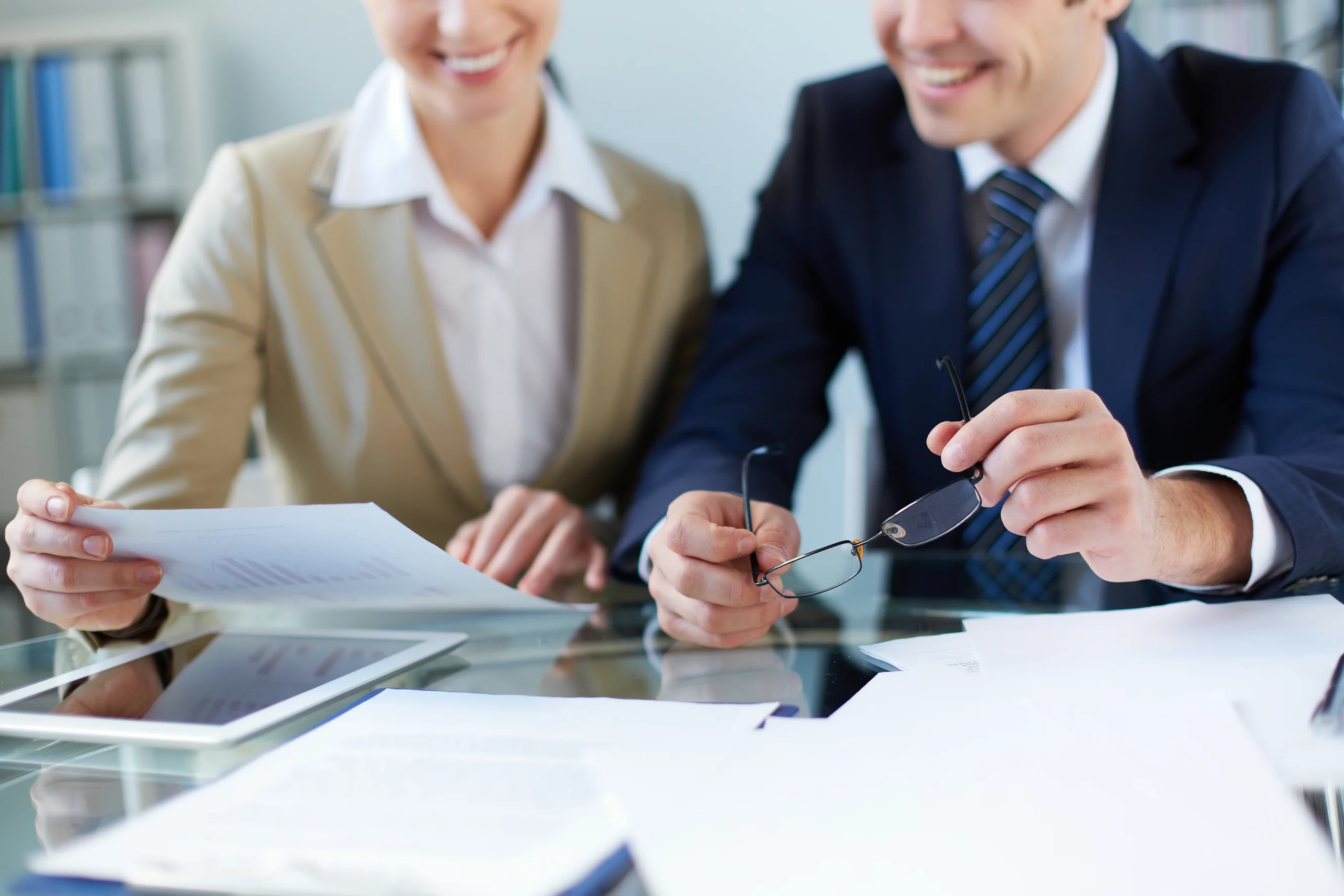 Two business people sitting at a desk practicing negotiation techniques while reviewing cross-cultural papers.