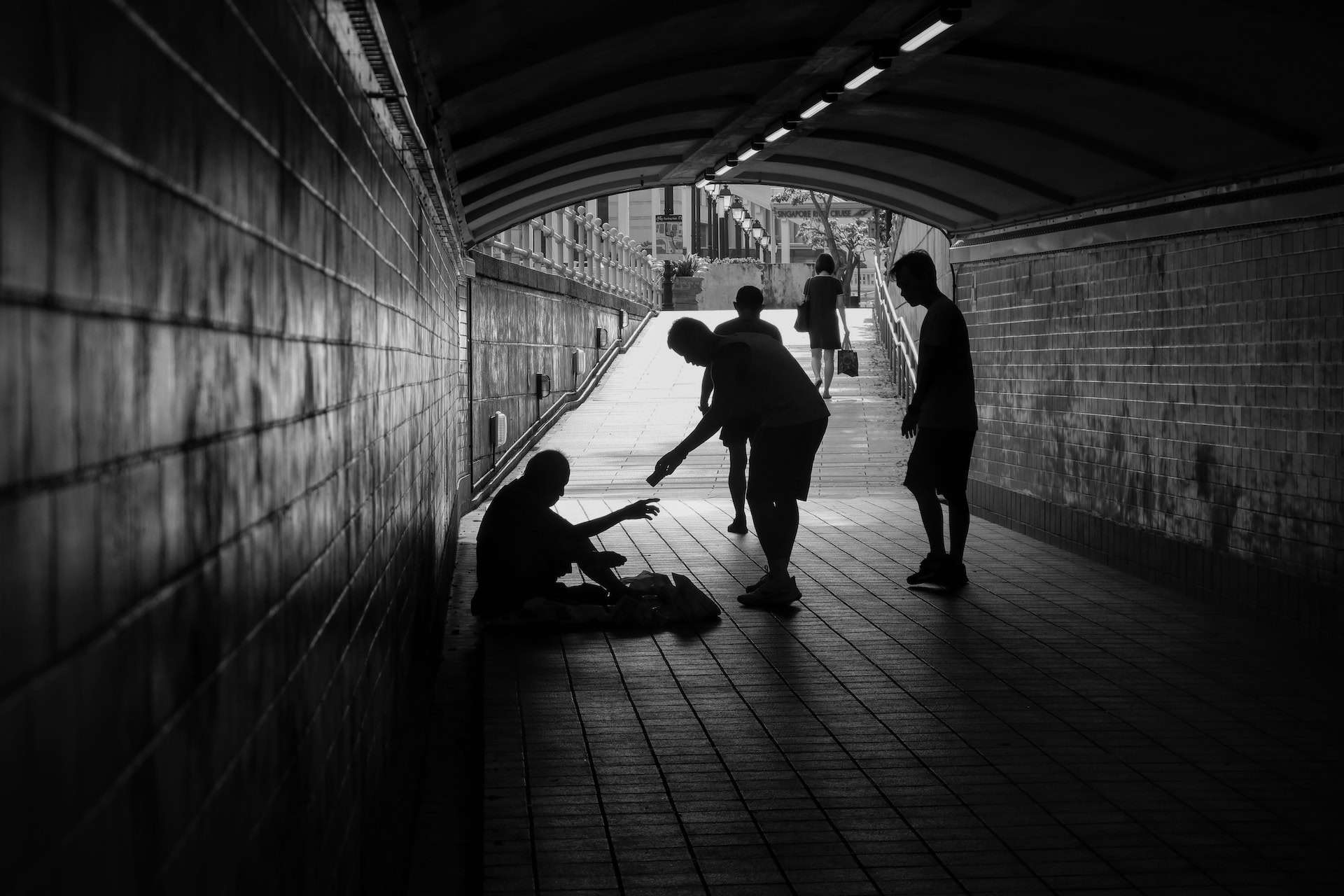 A black and white photo of a group of people in a tunnel, representing economic inequality.