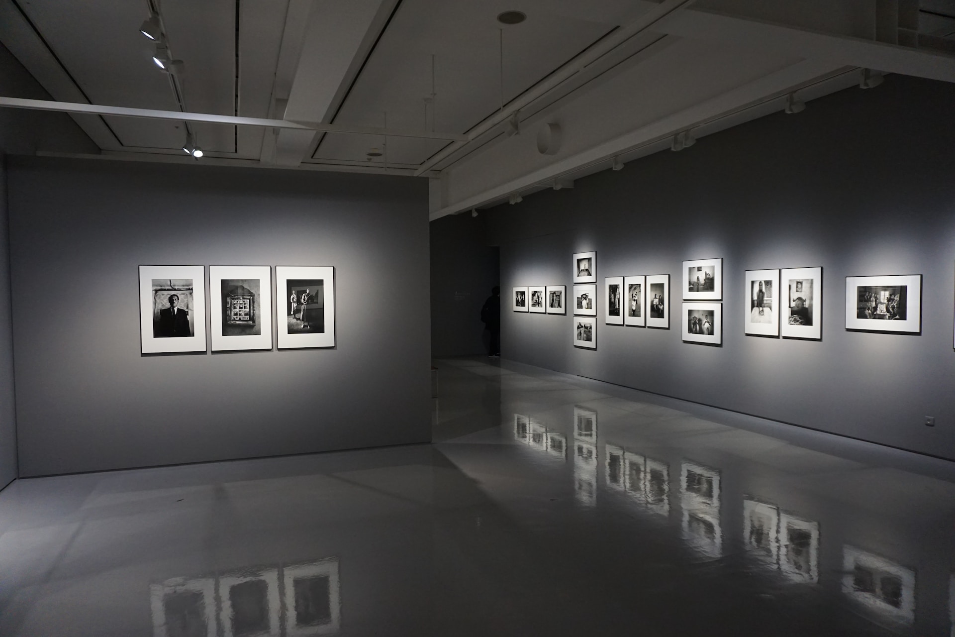 An international exhibition of black and white photographs in a dark room.