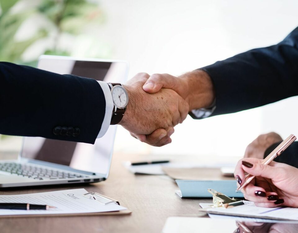 Two business people shaking hands at an international trade meeting, emphasizing compliance and ethical practices.