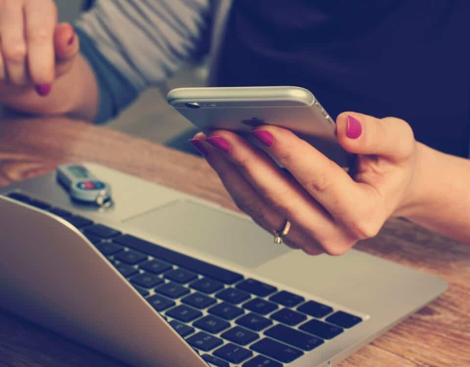 A woman utilizing localization strategies for global markets with a cell phone and a laptop.