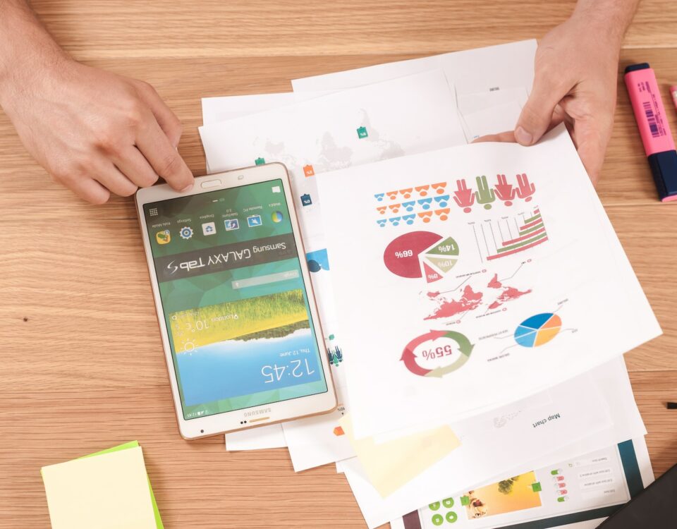 A person is using a smartphone to look at financing graphs on a table.