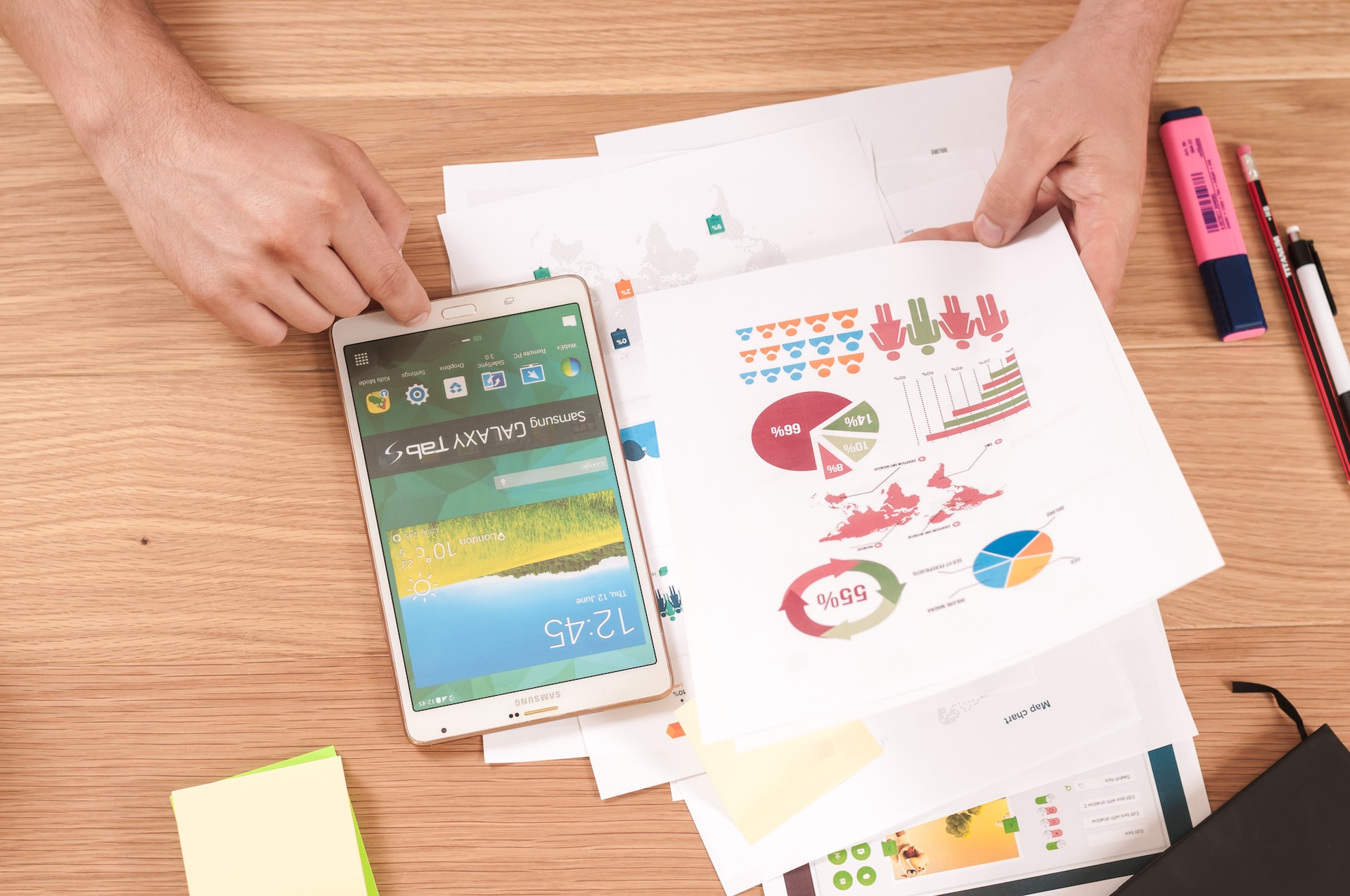 A person is using a smartphone to look at financing graphs on a table.