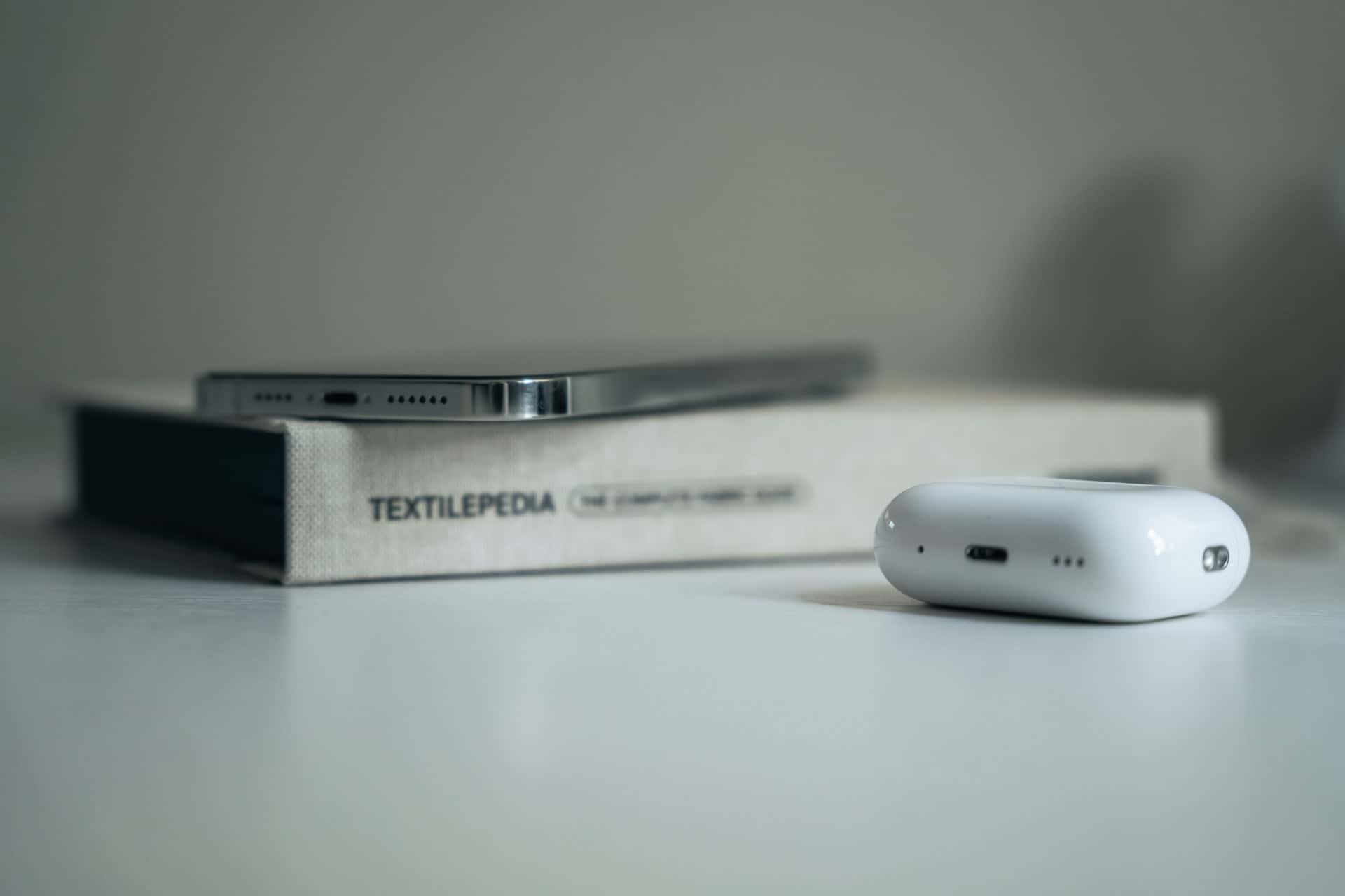 A specific product, the Apple AirPods, sitting on a table next to a book.