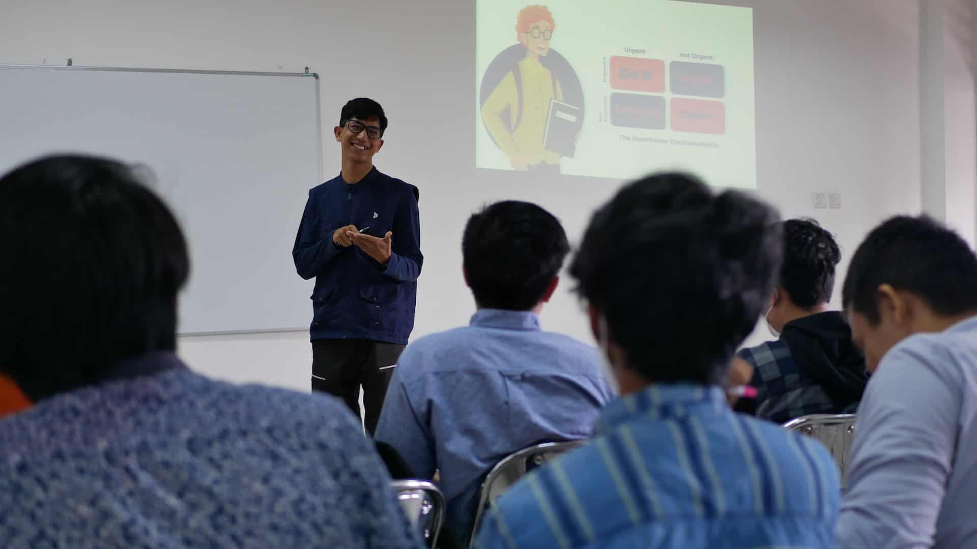 A man giving a presentation on International Trade to a group of people.