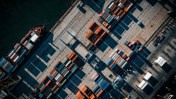 An aerial view of a container ship docked at a dock, highlighting the impact of trade disputes on global commerce.