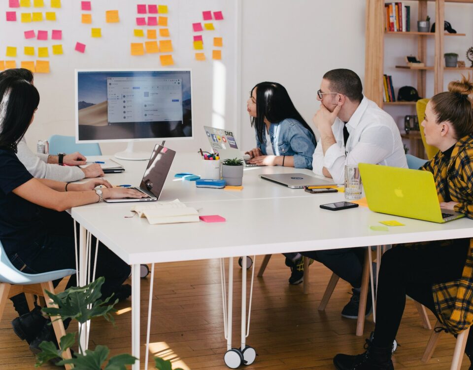 A group of people conducting market research and analysis, sitting around a table with laptops.