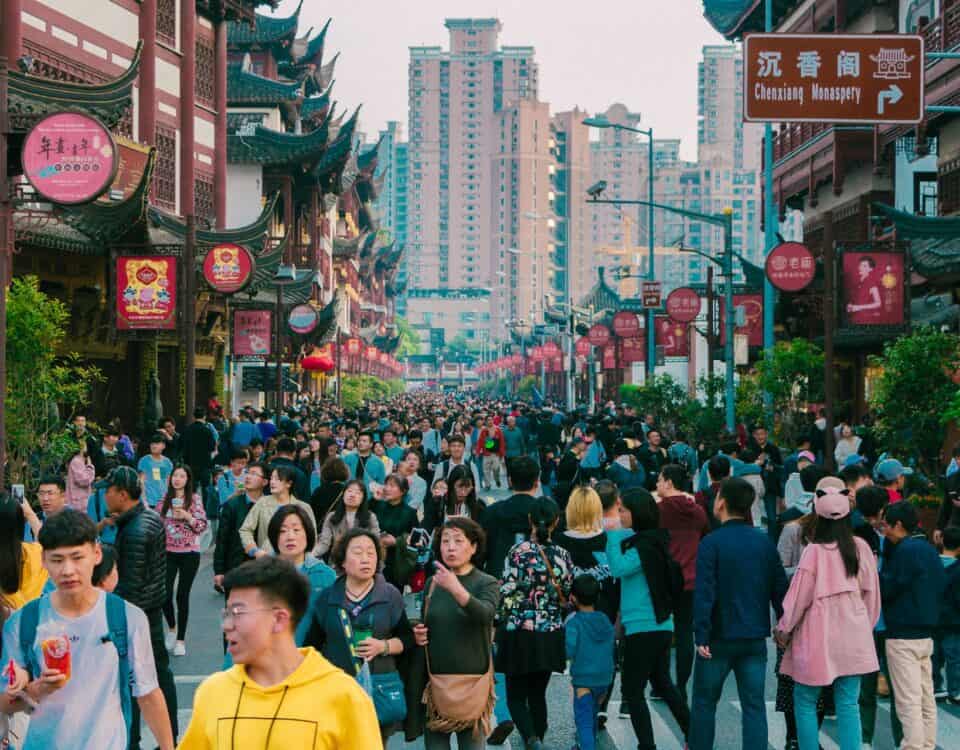 A crowd of people walking down a bustling street in an Asian city, exhibiting China's influence through its booming international trade.