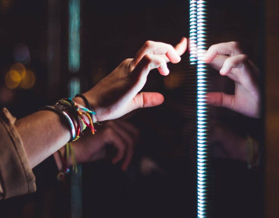 A person's hand reaching into a mirror, symbolizing the transformative role of technology in international trade.