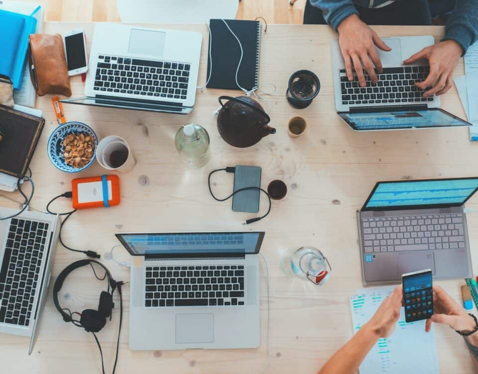 A group of people collaborating on digital products around a table with laptops.