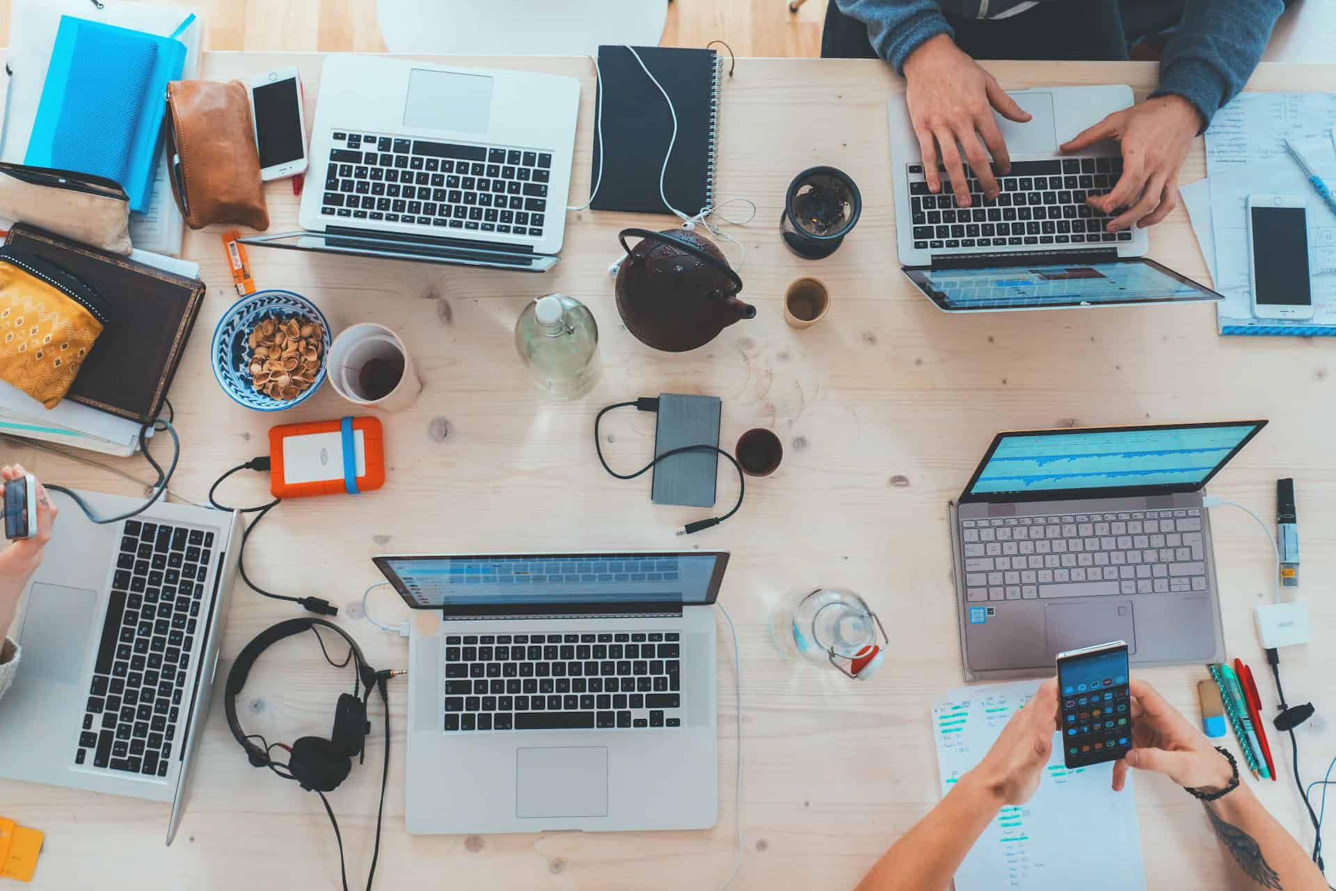 A group of people collaborating on digital products around a table with laptops.