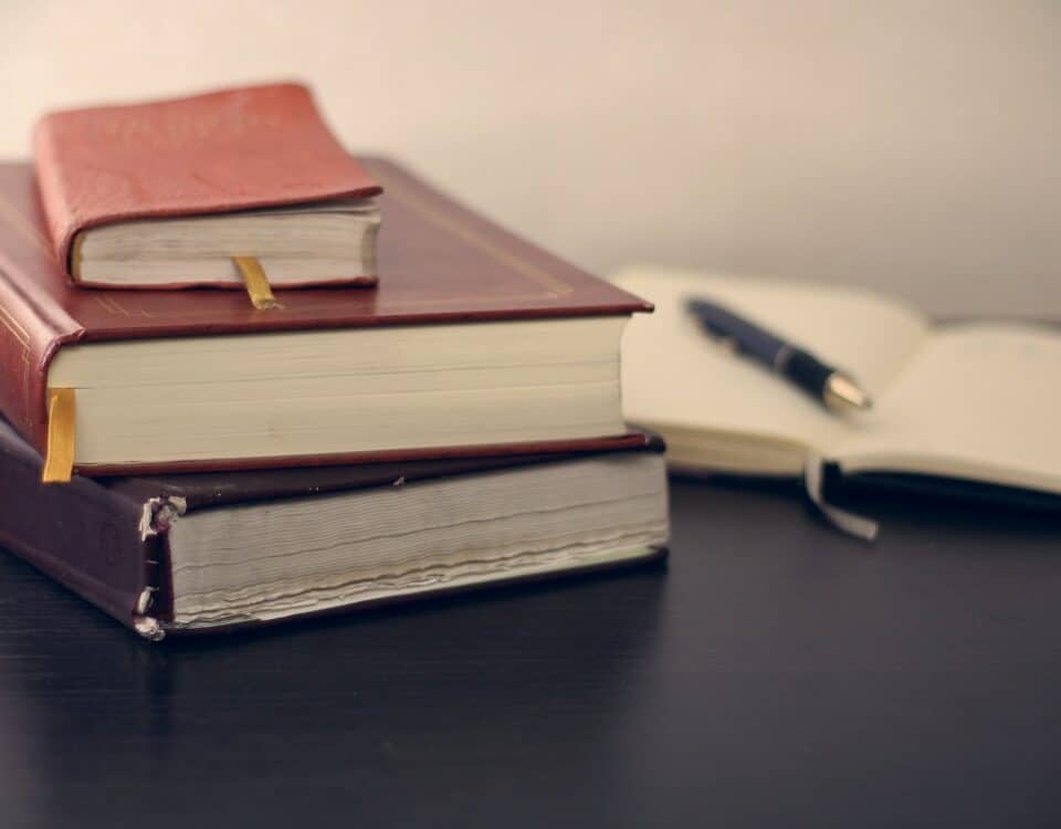 A stack of books and a pen on a table for understanding basics of international trade law.