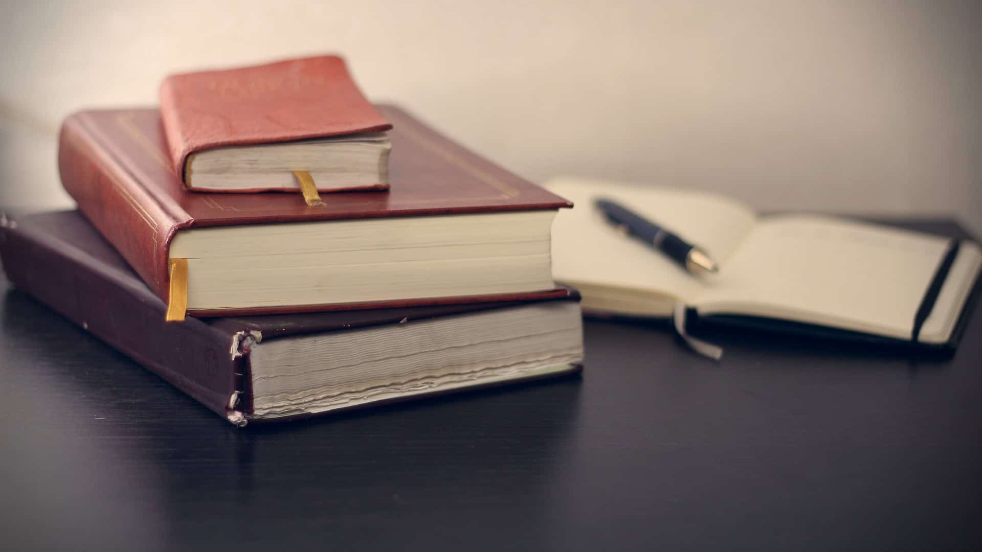 A stack of books and a pen on a table for understanding basics of international trade law.