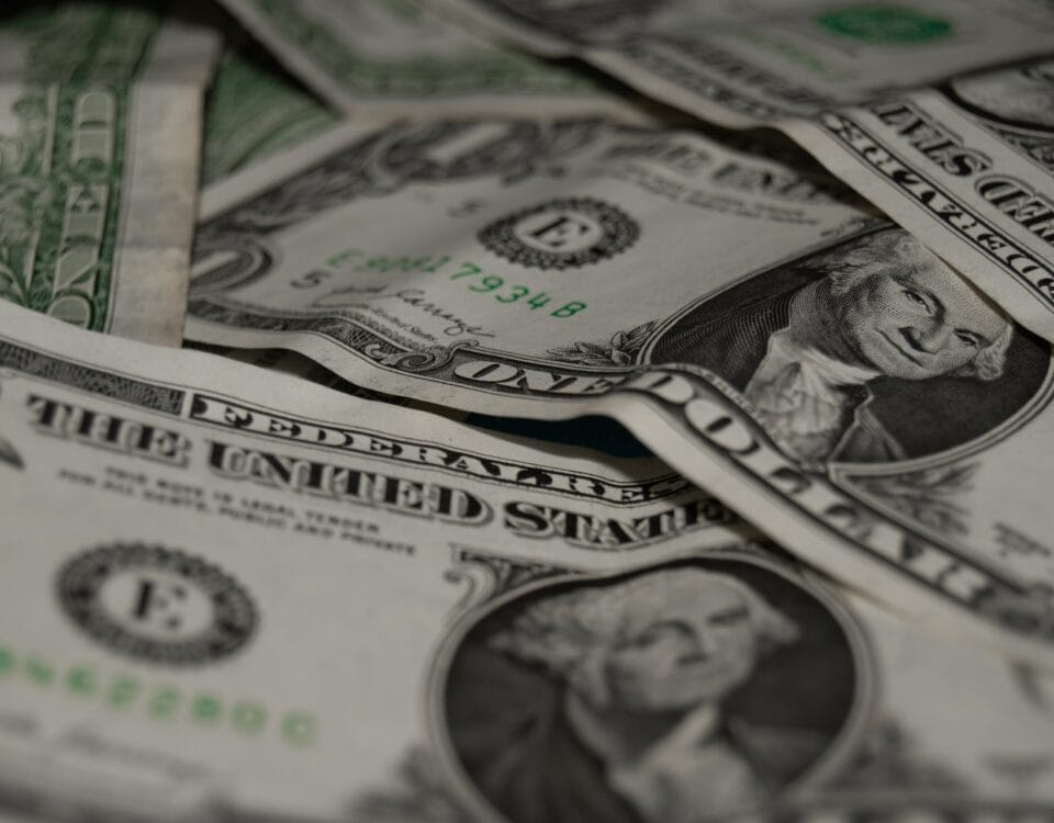 A pile of us dollar bills on a table, symbolizing the impact of global currency fluctuations and trade effects.