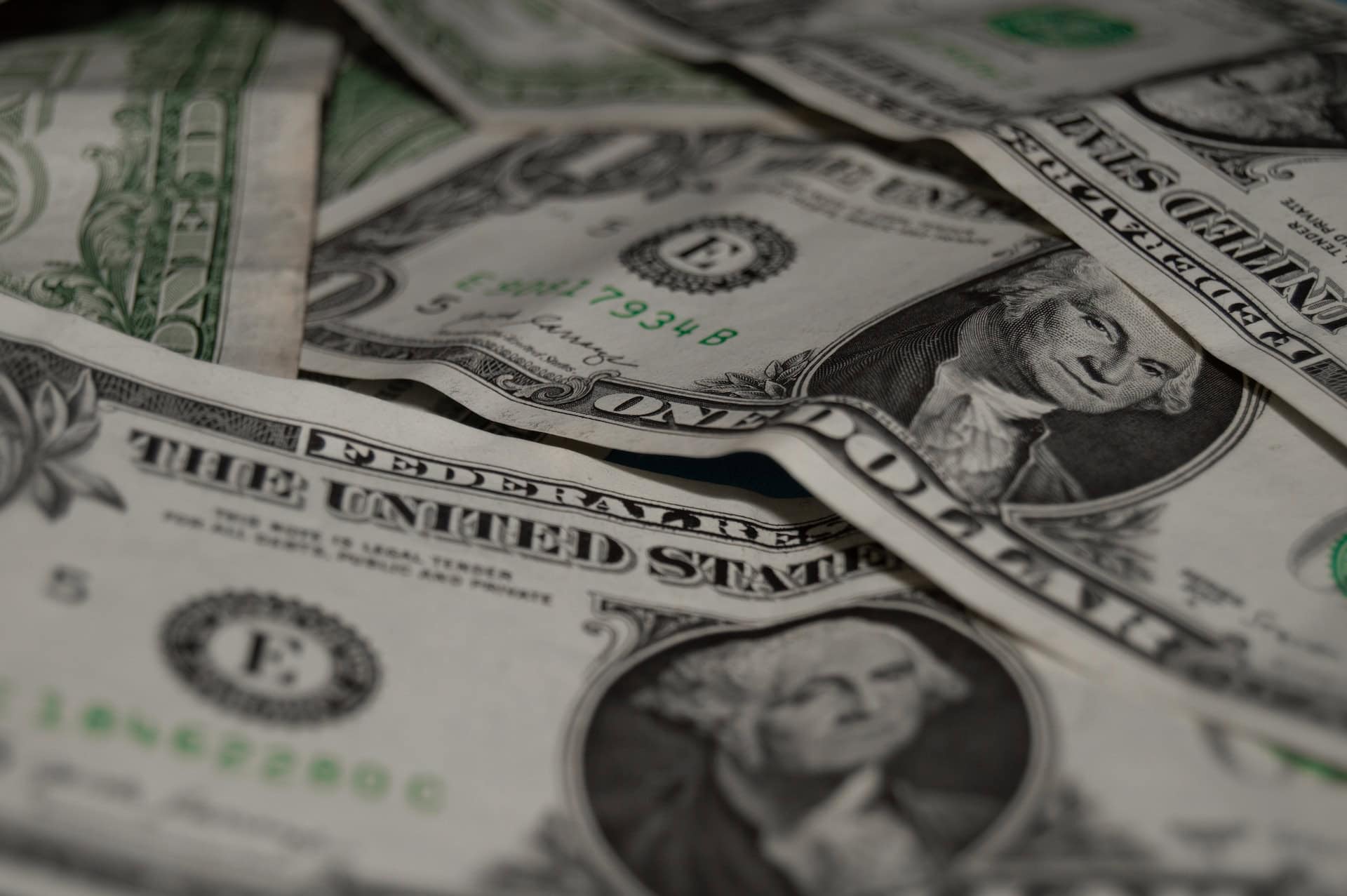 A pile of us dollar bills on a table, symbolizing the impact of global currency fluctuations and trade effects.