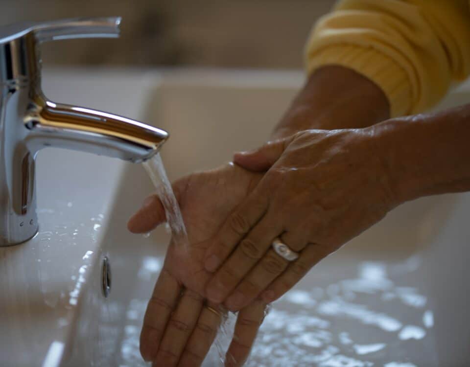 Amidst the pandemic recovery efforts, a person diligently practices good hygiene by washing their hands in a sink