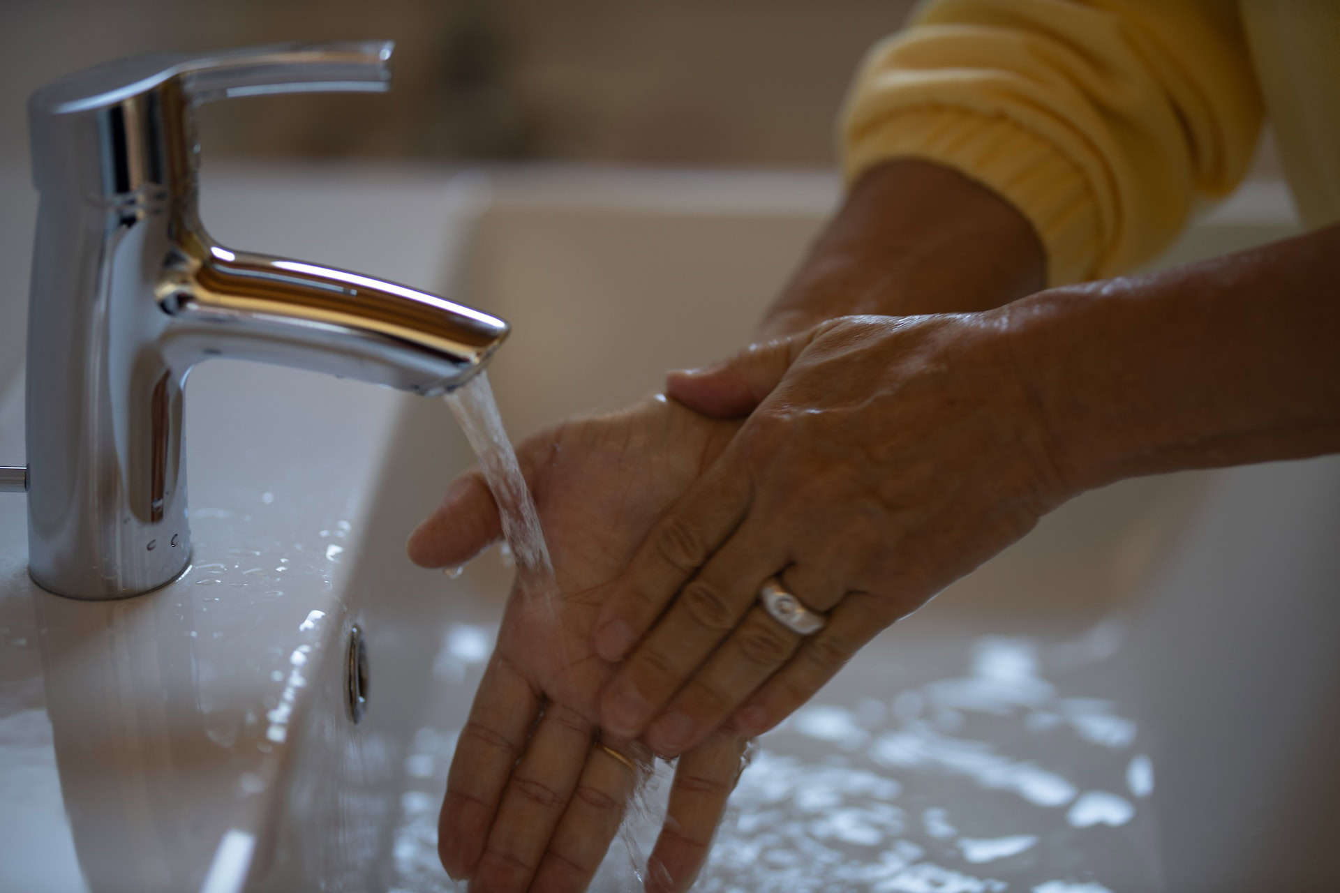 Amidst the pandemic recovery efforts, a person diligently practices good hygiene by washing their hands in a sink