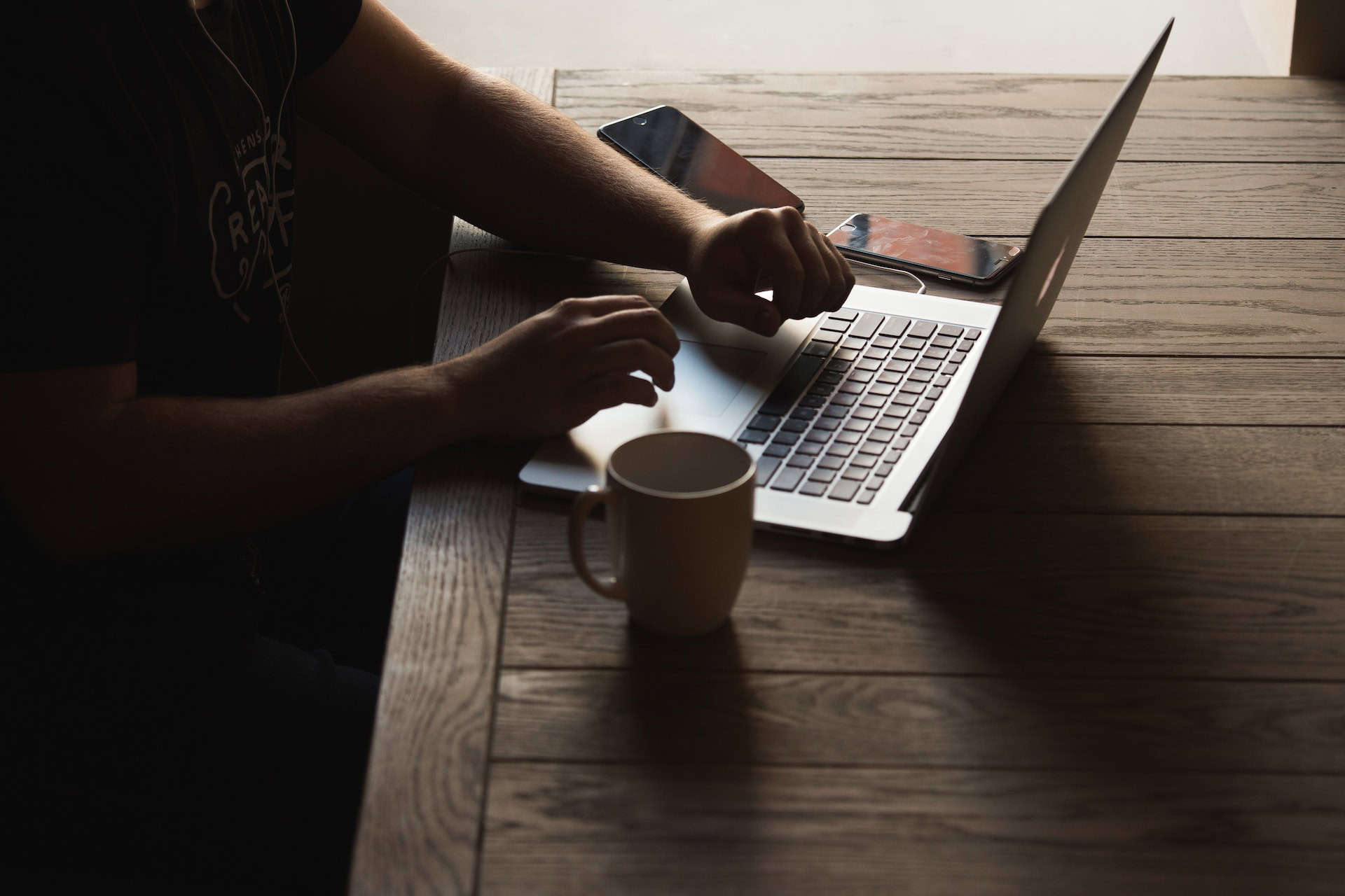 A man sitting at a table with a laptop and a cup of coffee, emphasizing sustainability practices in corporate social responsibility.