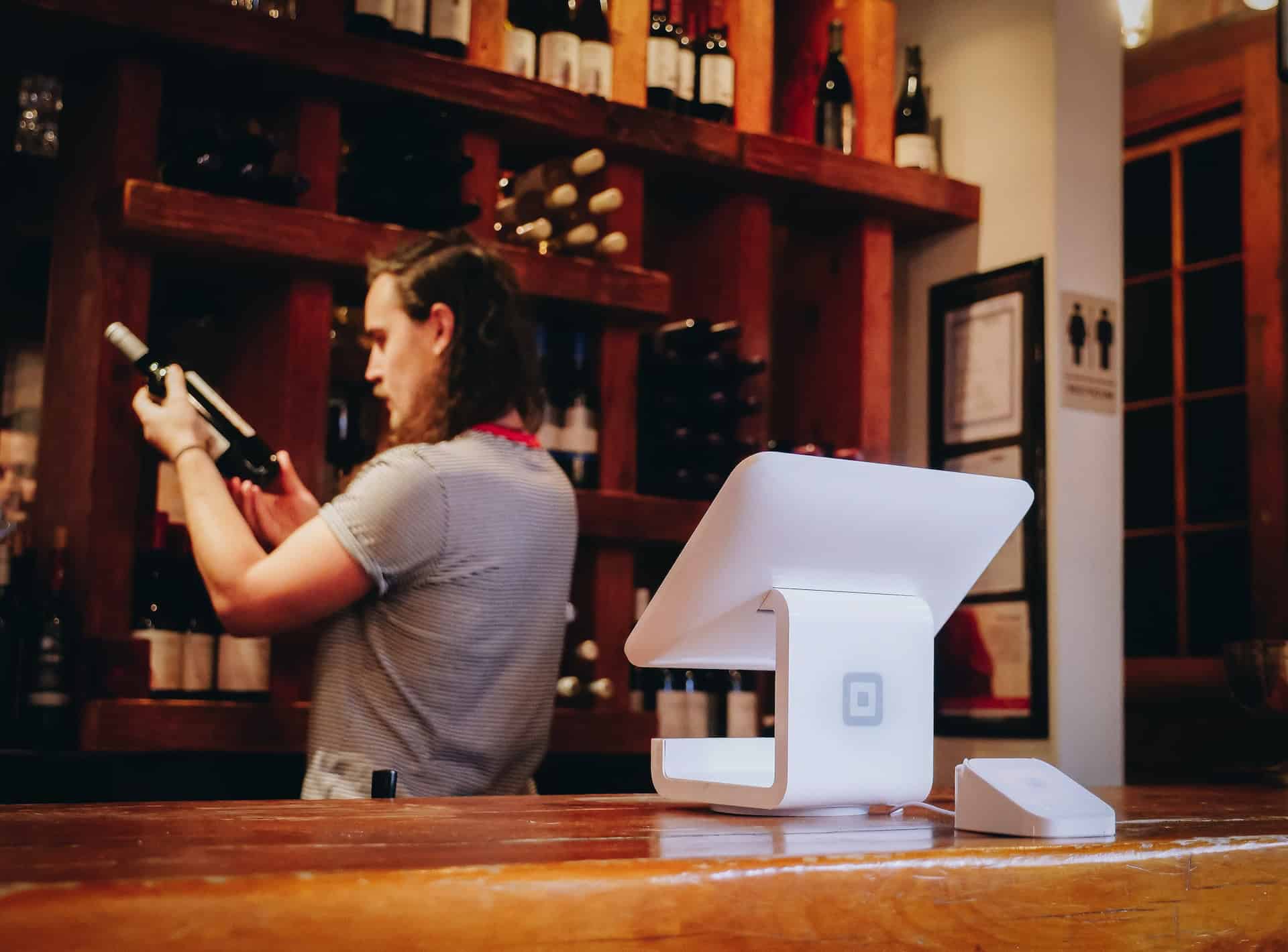 A man standing at a bar with a wine bottle in front of him, showcasing the ambiance of the e-commerce platform for wine localization.