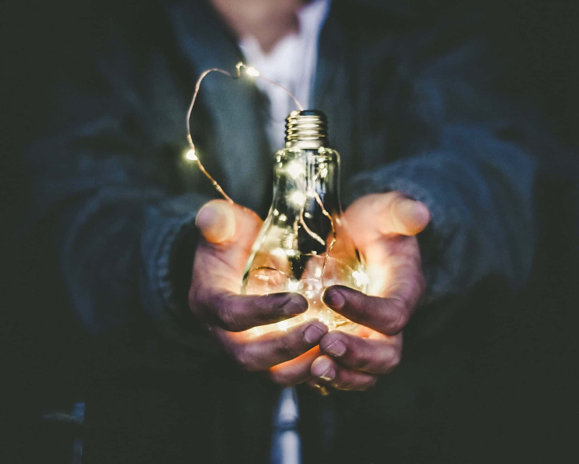 A person holding a light bulb, representing the emergence of innovative sectors and exporting opportunities.