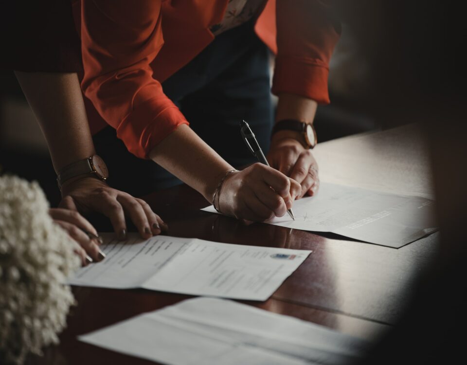 Two people signing export documentation at a table.