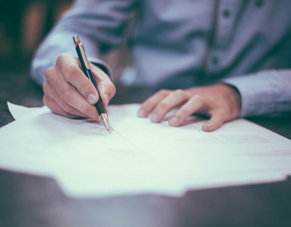 An individual engaging in international trade, negotiating and signing contracts using a pen.