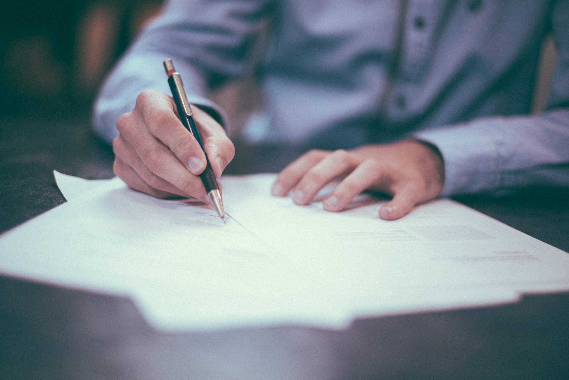 An individual engaging in international trade, negotiating and signing contracts using a pen.