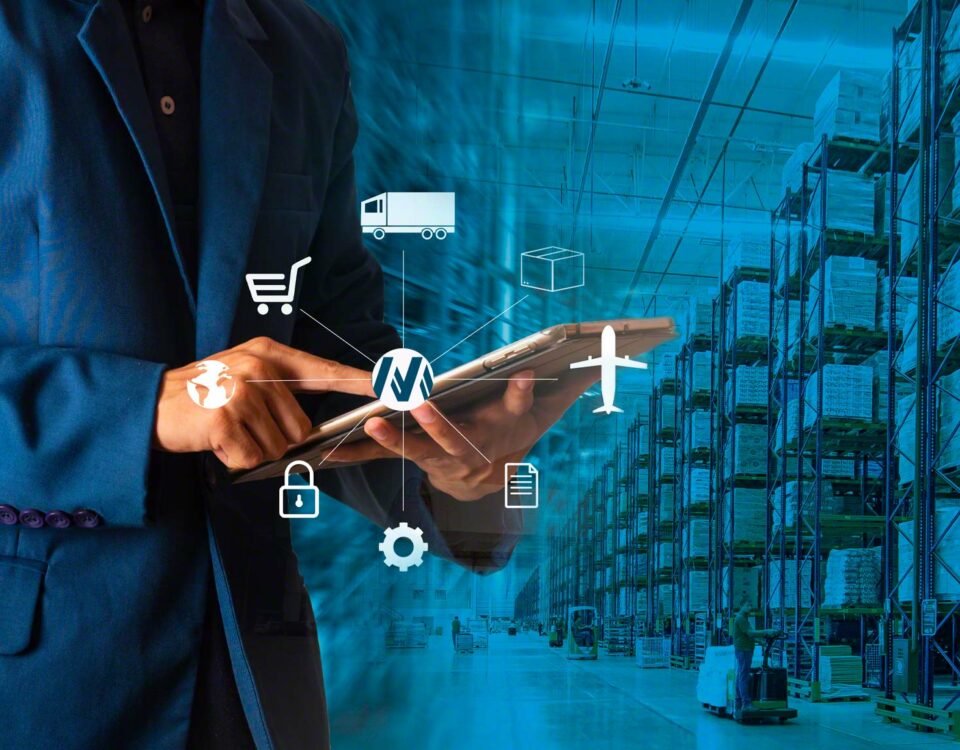 A man in a suit is using a tablet to manage supply chain operations in a warehouse.