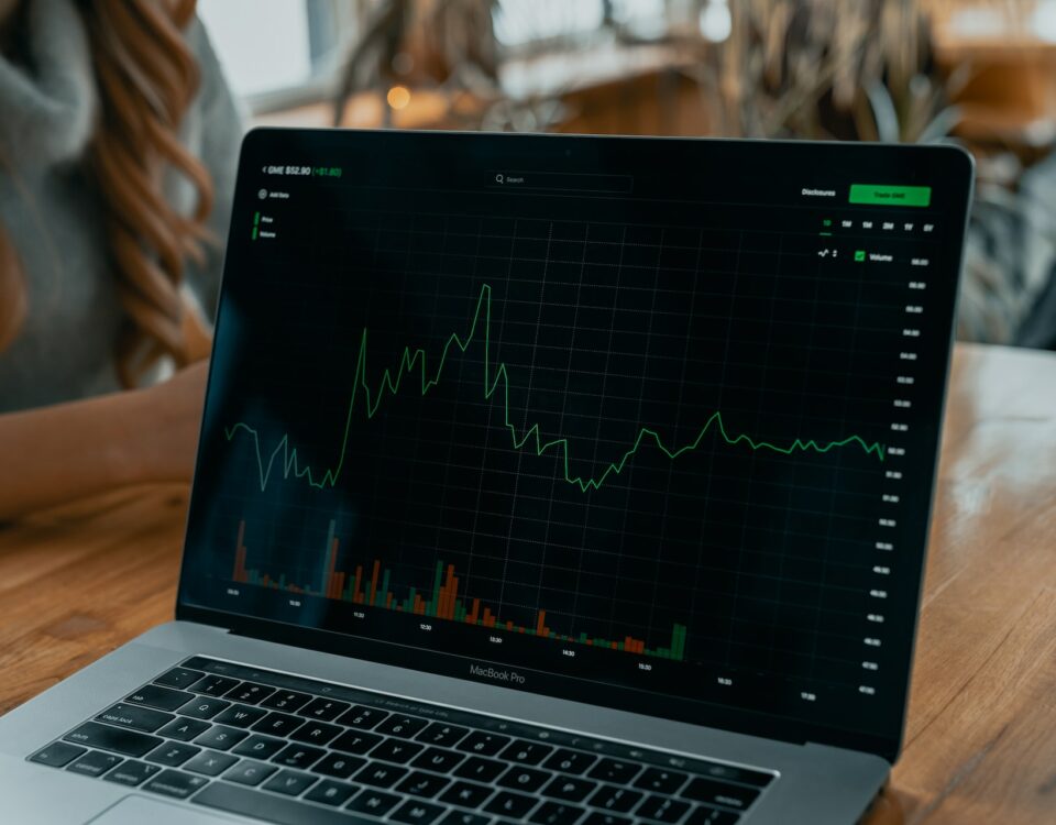 A woman is looking at a laptop with an international trade stock chart on it.