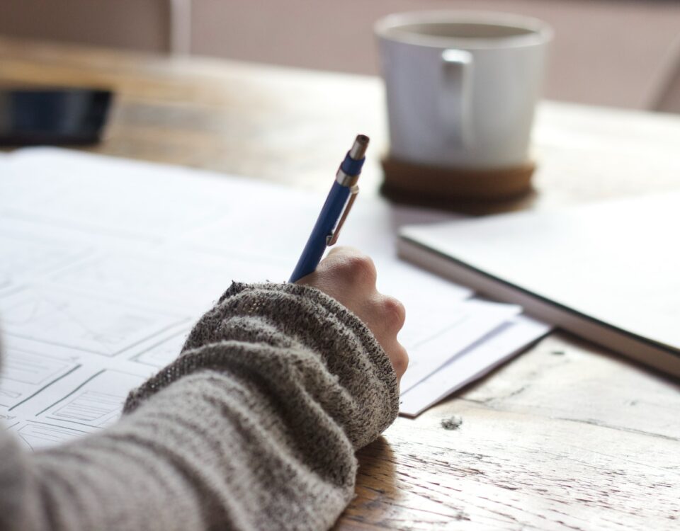 A person writing on a piece of paper at a desk, engaged in business negotiations.