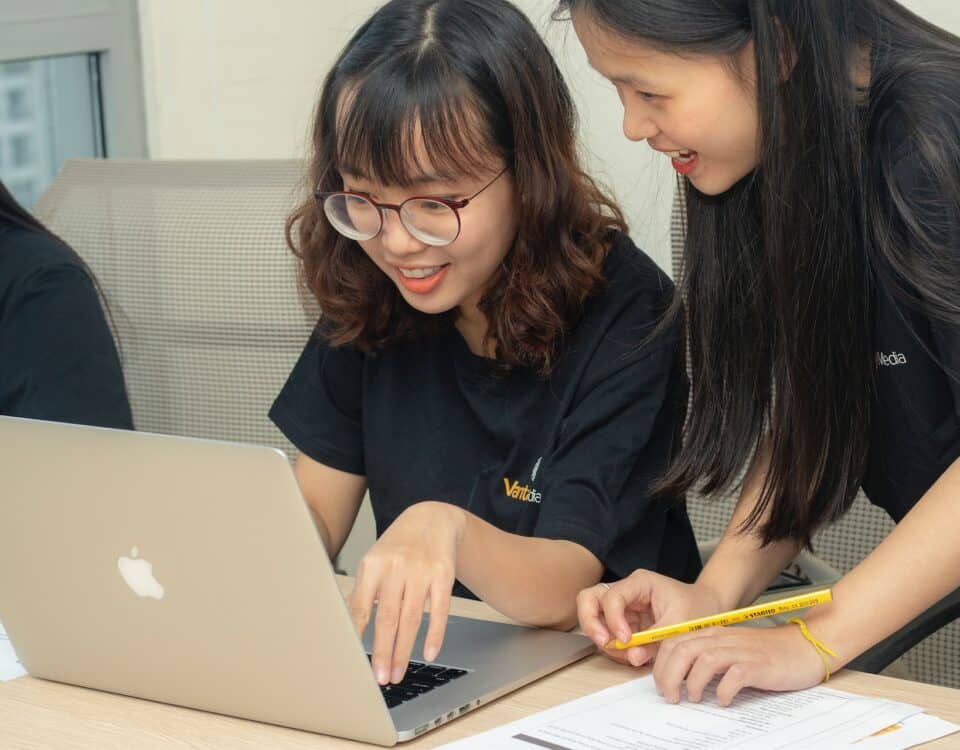 Three asian women working on a laptop while conducting competitive analysis and gathering market intelligence.