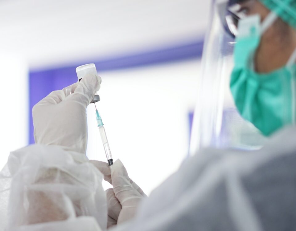 A nurse is holding a syringe in a hospital while dealing with global pandemics.