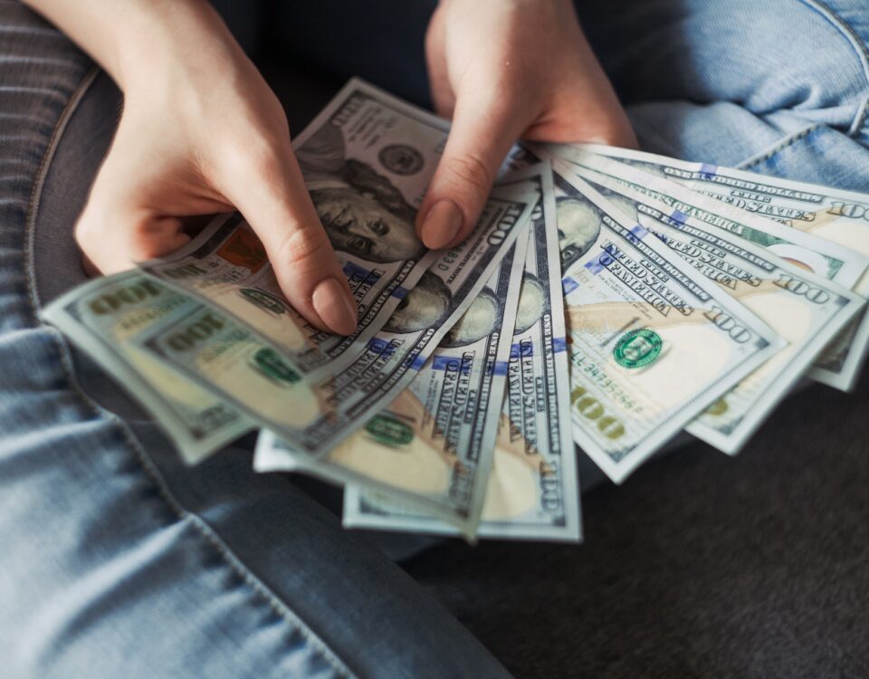 A woman's hands managing export financing with a stack of dollar bills.