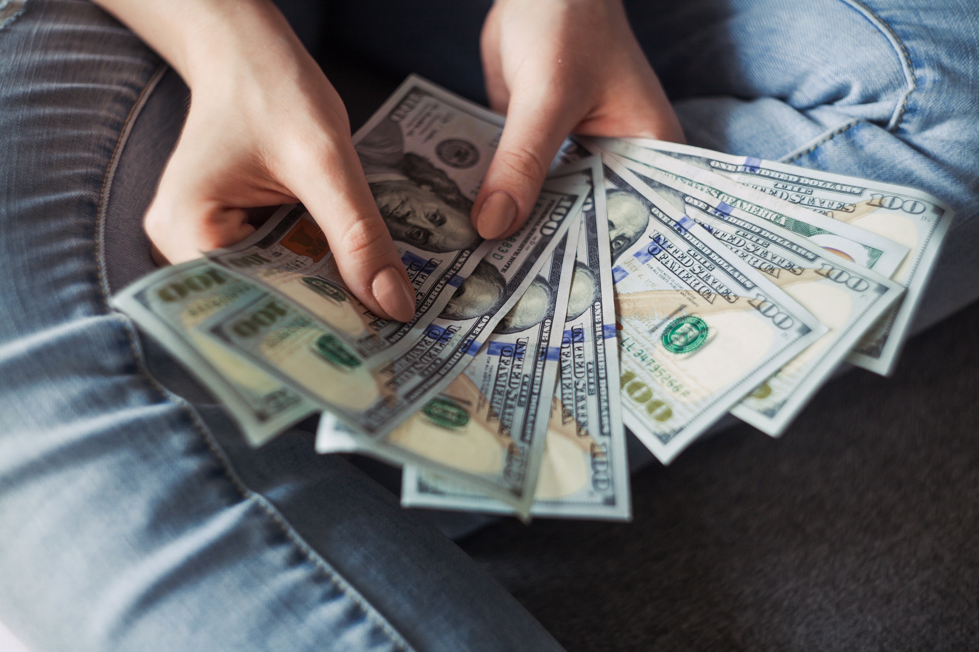 A woman's hands managing export financing with a stack of dollar bills.