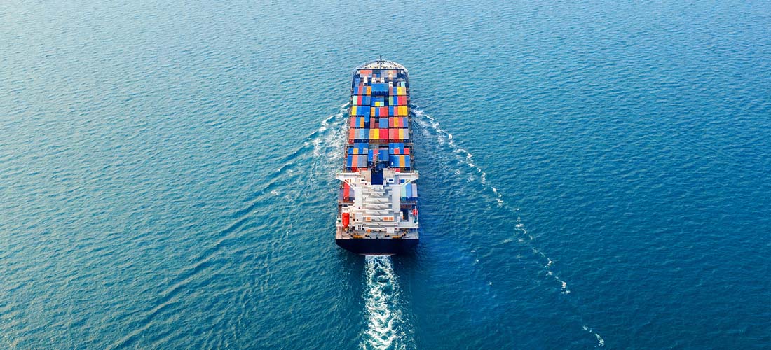 An aerial view of a container ship in the ocean providing export market analysis.