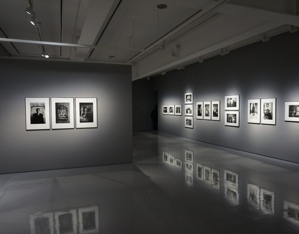 An international exhibition of black and white photographs in a dark room.