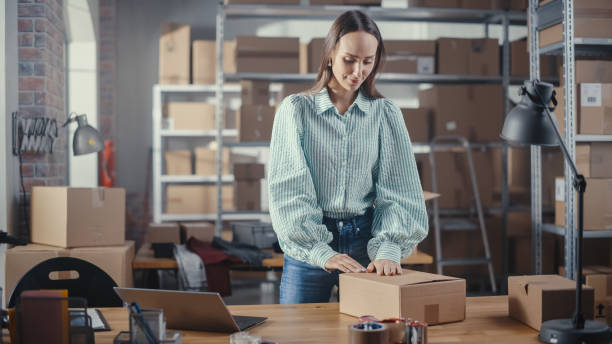 A robust woman is opening an export box in a developing warehouse.