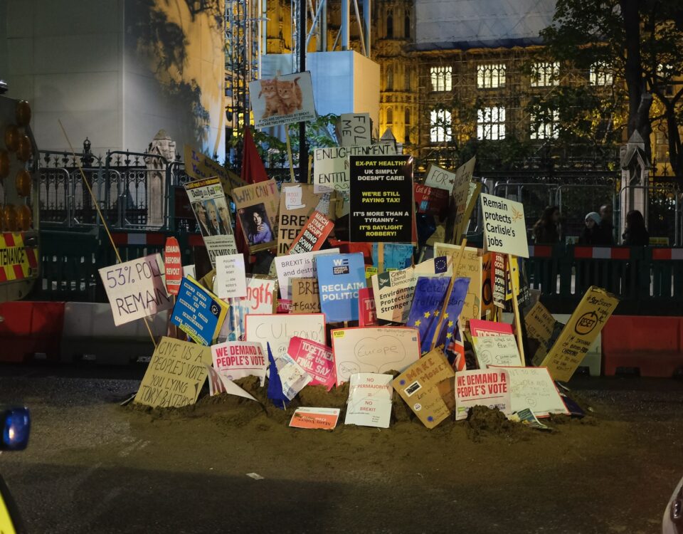 A large pile of protest signs related to Brexit scattered in front of a building.